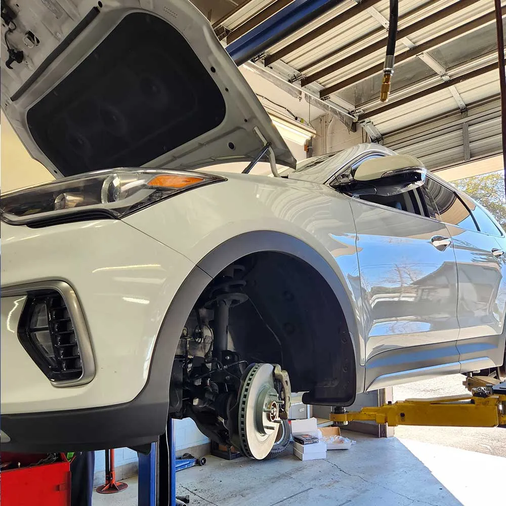 Car on lift with open hood in garage.