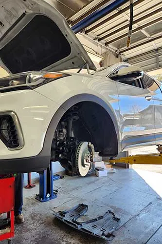 Car on lift for wheel maintenance in garage.
